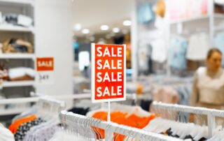 Sale in a clothing store. Red sign saying Sale inside the store, blurred background. Product